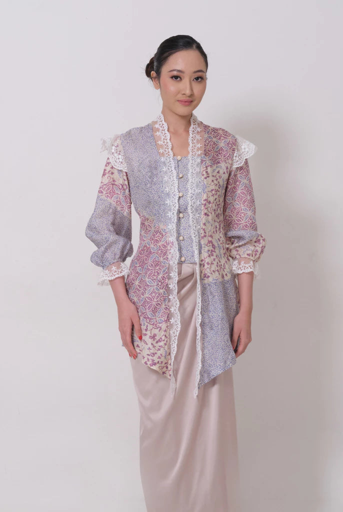 A woman wearing a traditional batik viscose kebaya by Kartinis Label with lace details and a keyhole front neckline in a misty print.
