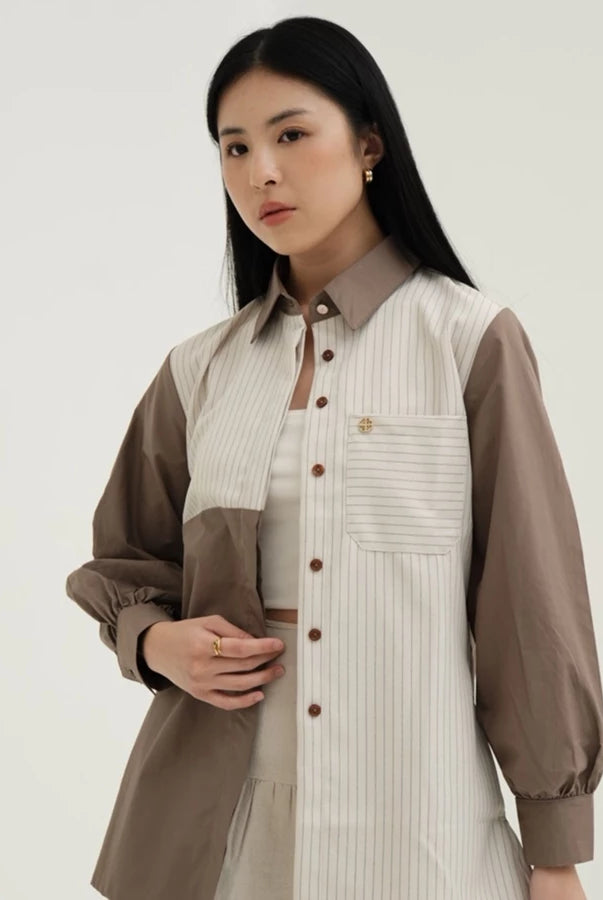 Woman wearing a two-tone blouse by Tunique with a neutral background