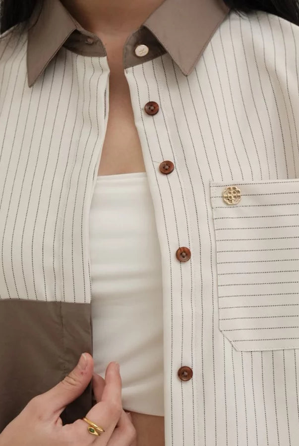 Close-up of a person wearing a brown and beige striped blouse by Tunique with a collar.