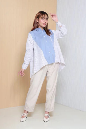 Woman wearing a stripped light blue and checkered white shirt by Casa Elana with beige pants against a neutral background