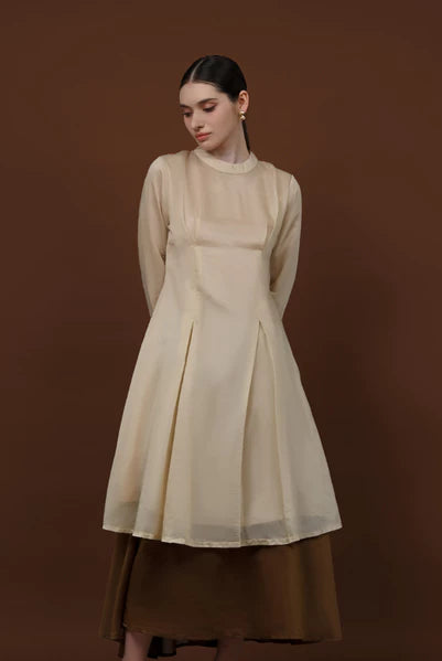 Seorang wanita memakai tunik berlengan panjang berwarna almond dari brand Kasa Heritage.