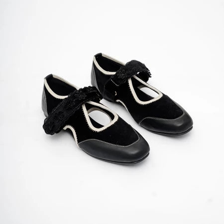 Pair of black shoes with decorative floral strap by Dianable on a white background