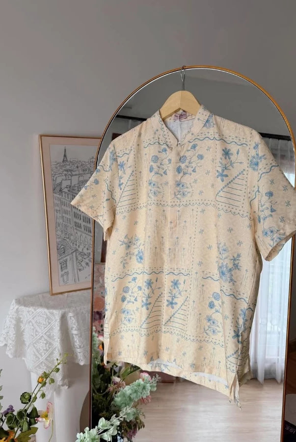 Yellow floral patterned shirt by Haidee Orlin on a hanger against a neutral wall with decor elements.