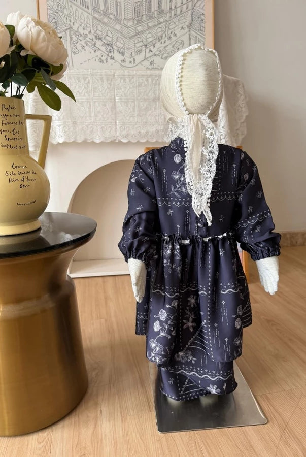 Mannequin wearing a navy floral dress by Haidee Orlin with white patterns on a wooden floor.