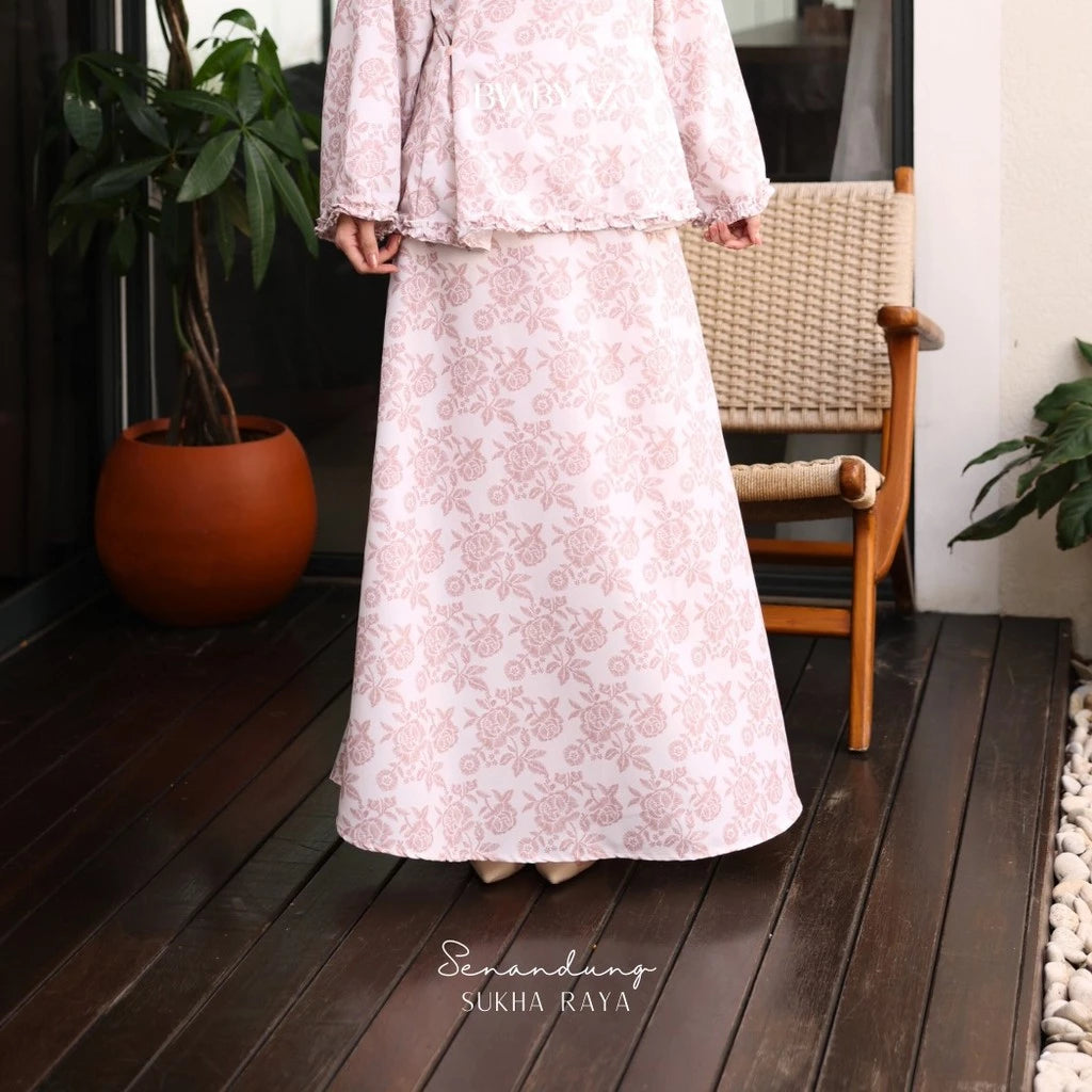 A person wearing a long floral skirt with a pink color scheme, featuring an A-line silhouette from BWBYAZ.