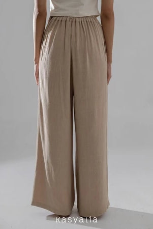 Light brown wide-leg pants worn by a person on a plain background with 'kasyalia' branding.