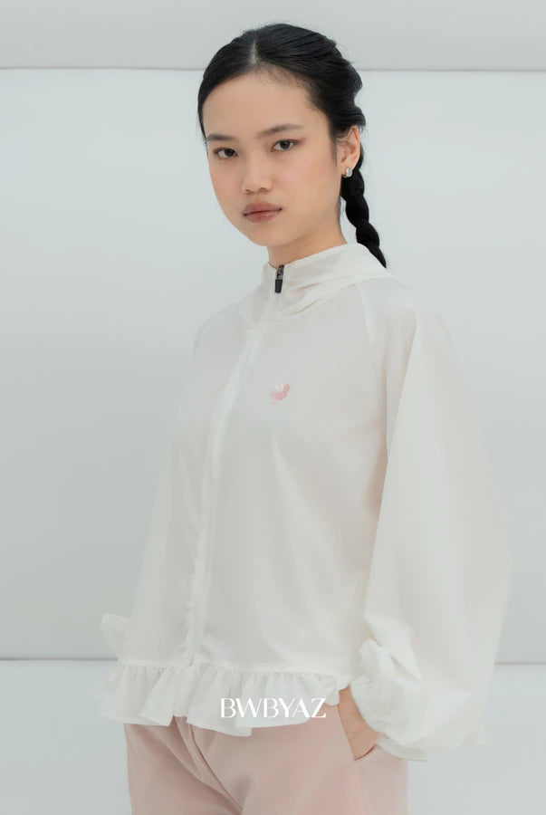 A model wearing a white lightweight zip-up windbreaker jacket by BWBYAZ with a small pink embroidered logo on the chest, paired with light pink pants, set against a minimalist white studio background.