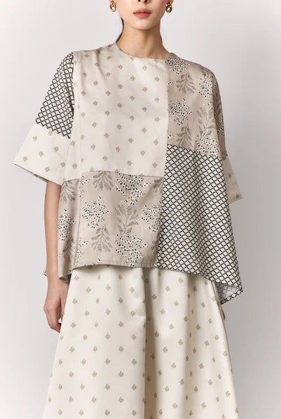 Woman wearing a two-piece outfit with a patterned blouse and skirt by Studio Tui on a white background