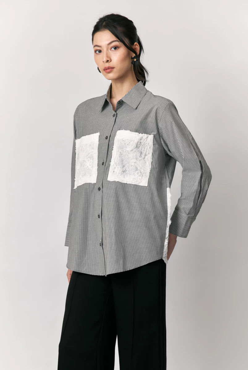Woman wearing a black striped shirt by Studio Tui with white lace pockets design on a plain background
