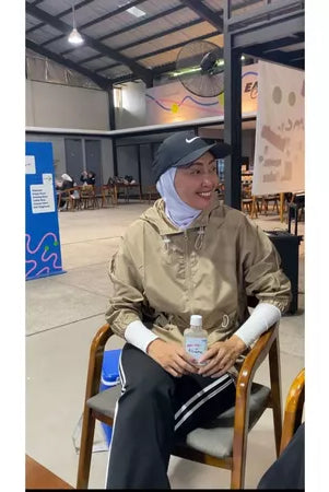 Person wearing latte-colored track jacket by Abame in an indoor setting