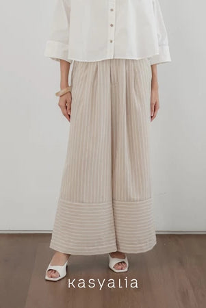 Person wearing a white shirt and beige wide-leg striped pants on a plain background with 'kasyalia' branding.