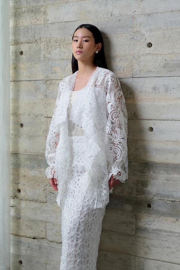 Woman in a white lace vest by Kasa Heritage standing against a textured wall.