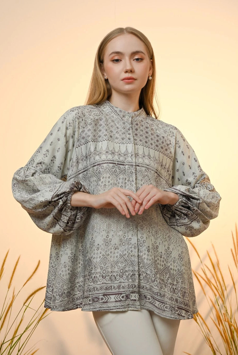 A woman wearing a light aqua colored Kamari blouse by Kasa Heritage with ethnic print and puffy sleeves, standing against a neutral backdrop.
