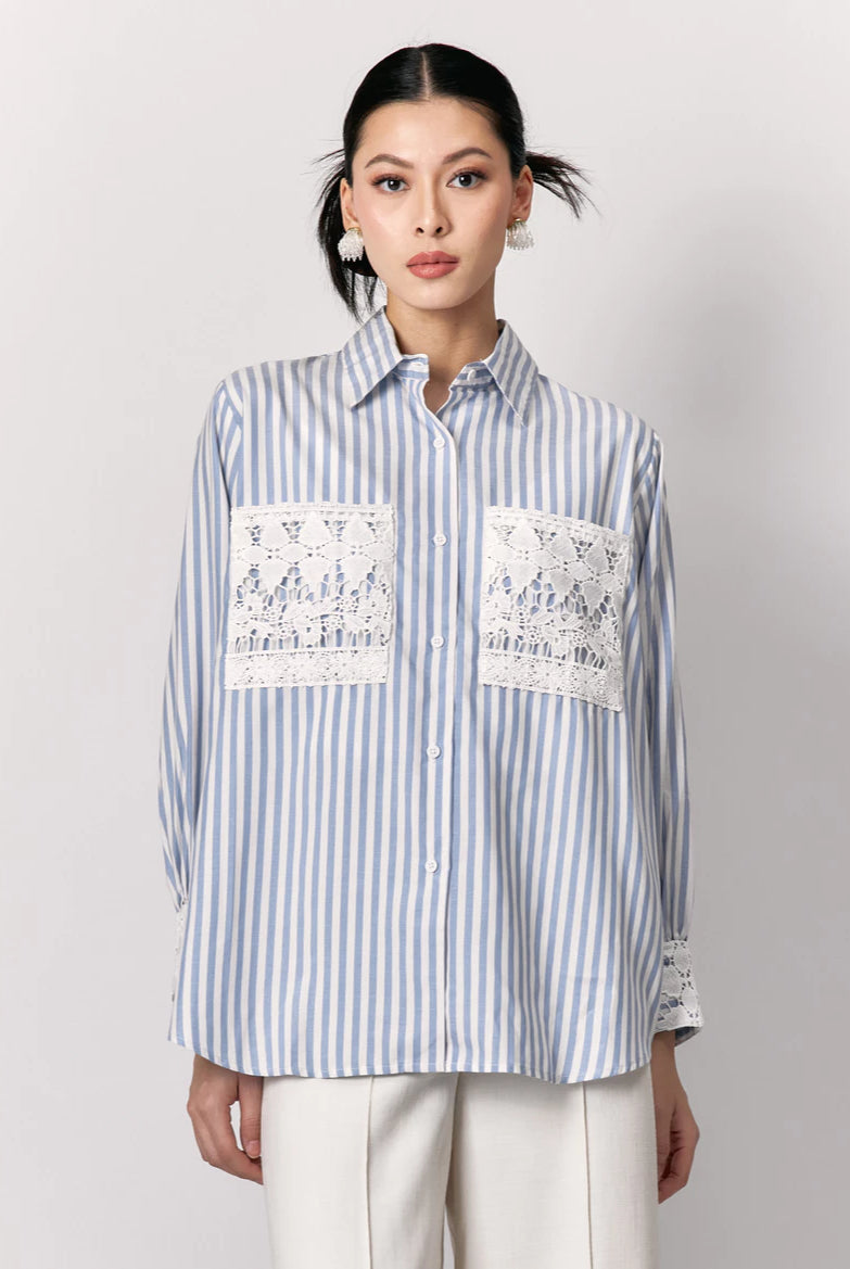 Woman wearing a blue and white striped shirt by Studio Tui with lace details on a plain background