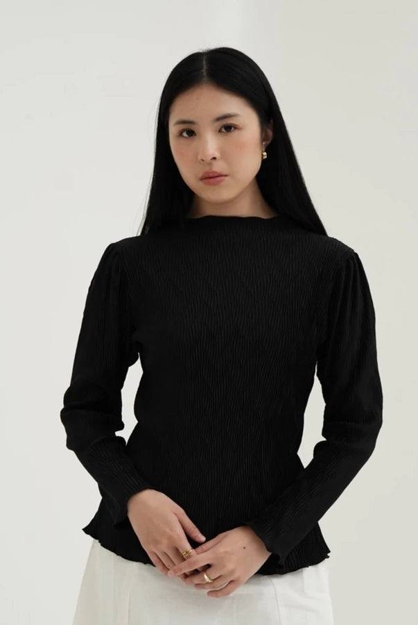 Woman wearing a black long-sleeve top by Tunique against a white background