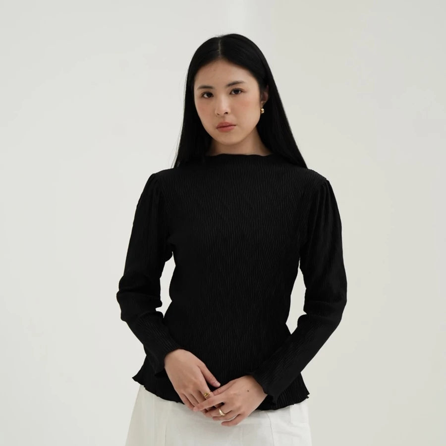 Woman wearing a black long-sleeve top by Tunique against a white background