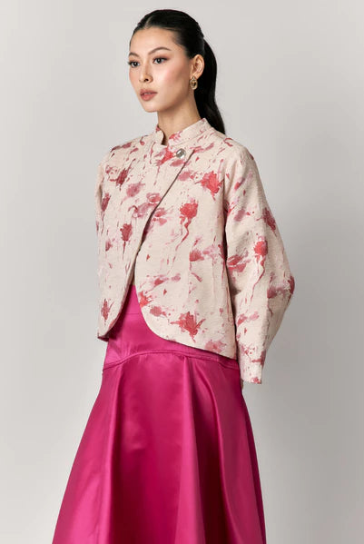 Woman wearing a floral blazer by Studio Tui and pink skirt on a gray background