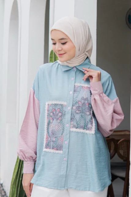 Woman wearing a light blue and pink shirt with floral patterns by Casa Elana.