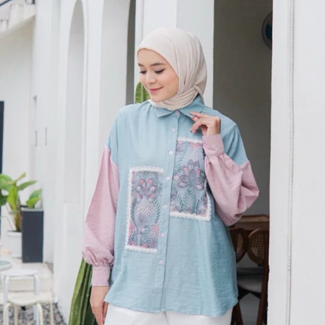 Woman wearing a light blue and pink shirt with floral patterns by Casa Elana.