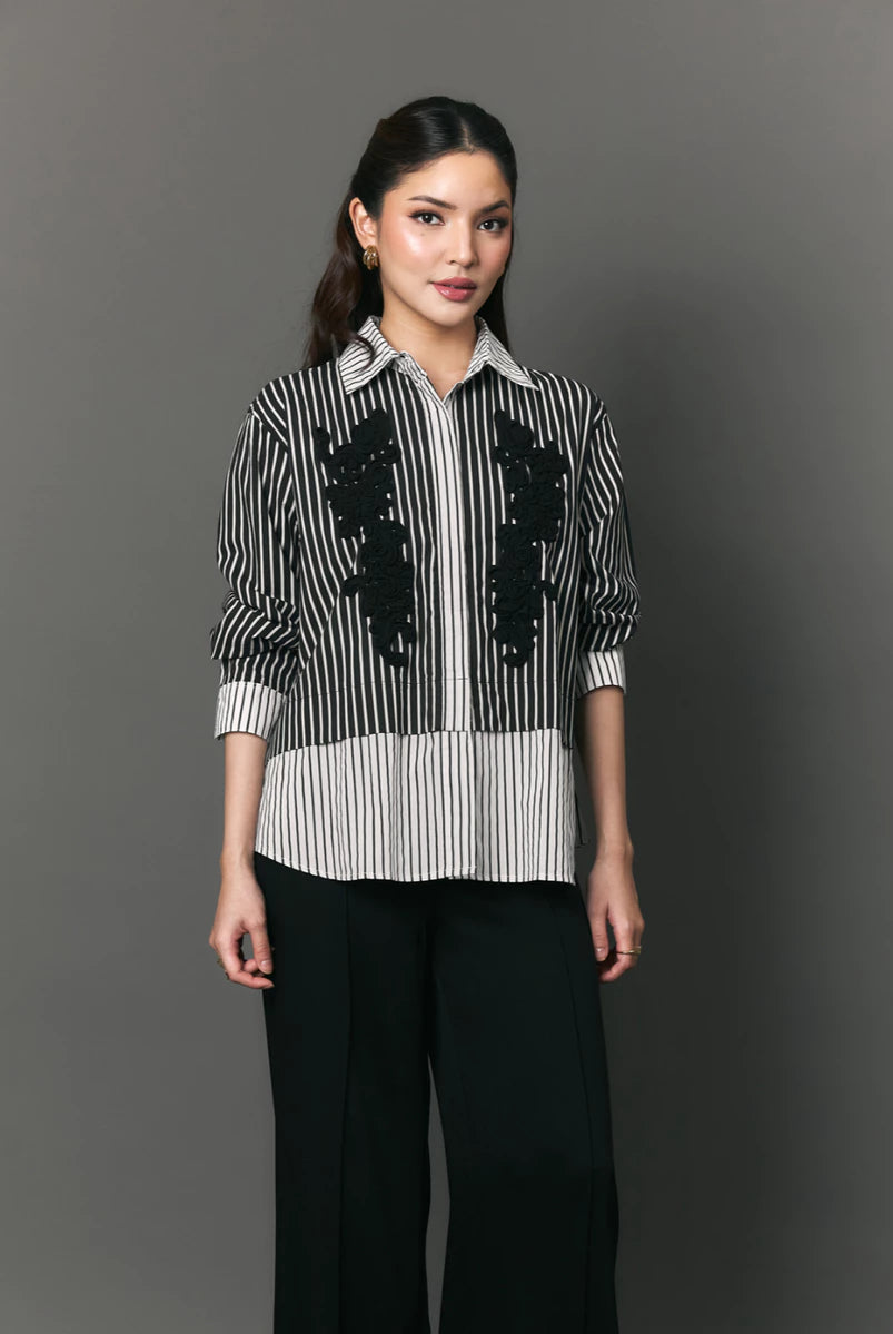 Woman wearing a black and white striped shirt with floral patterns by Studio Tui on a gray background