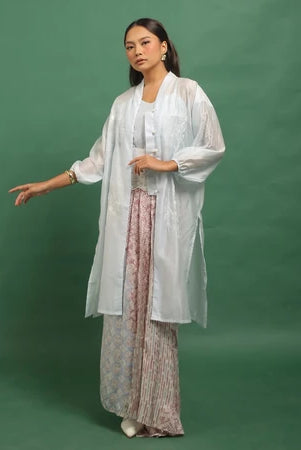 Woman wearing a light blue kebaya by Kartinis Label with a sheer overlay against a green background