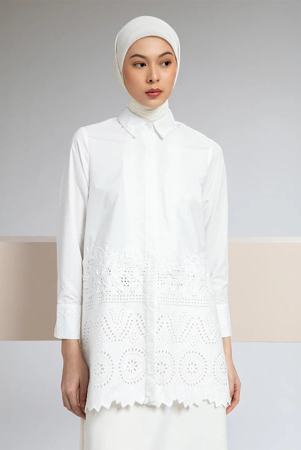 Woman wearing a white shirt by Hijabchic with lace details against a neutral background