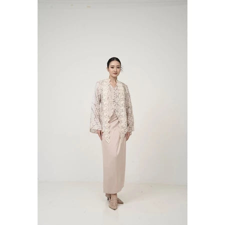 Woman wearing a patterned kebaya by Kartinis Label and beige skirt on a white background
