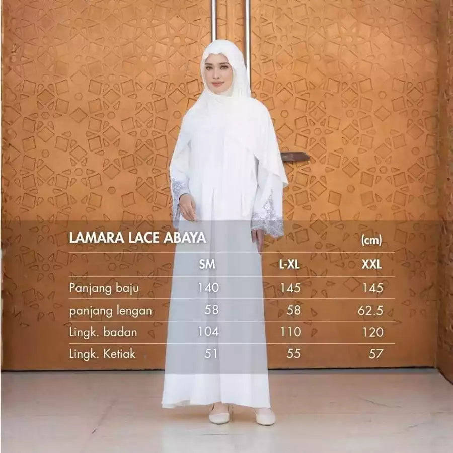 Woman wearing a white lace abaya with size chart against an orange patterned wall.