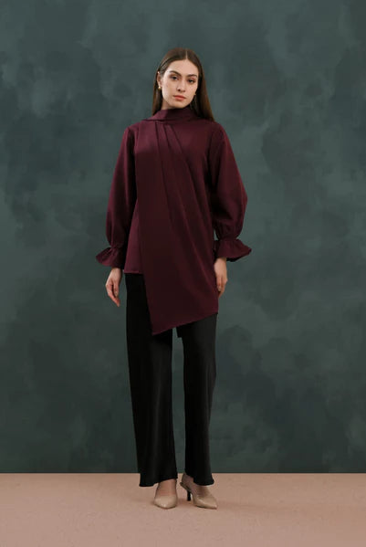 Woman wearing a burgundy blouse by Kasa Heritage and black pants against a dark green background