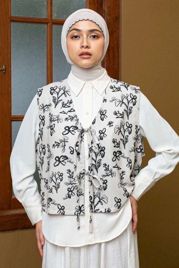 Woman wearing a cream-colored with a black floral patterned vest by Lozy Hijab in front of a window.