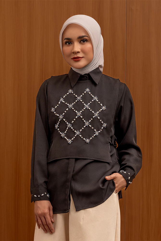 Woman wearing a black shirt by Jenna & Kaia with a geometric pattern against a wooden background
