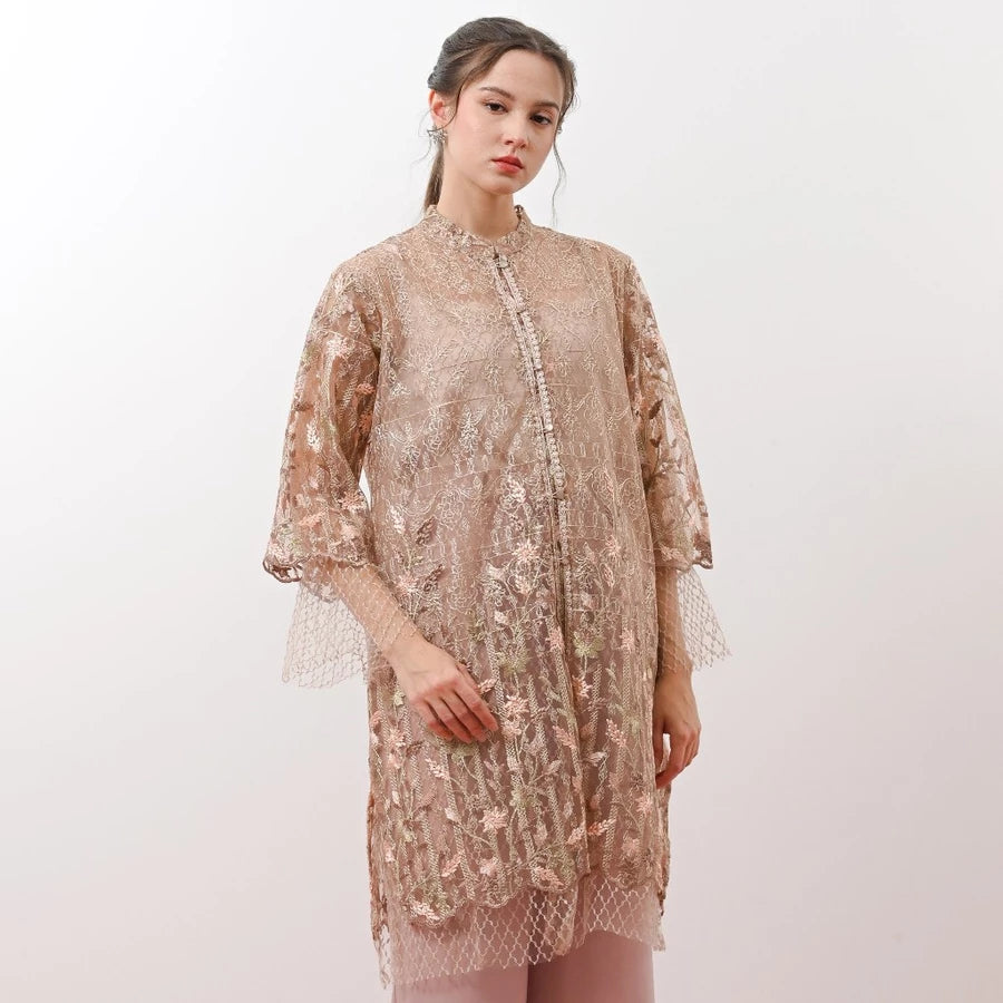Woman wearing a beige lace tunic by Holy Peony against a white background.
Seorang wanita mengenakan tunik renda berwarna beige dari Holy Peony dengan latar belakang putih.