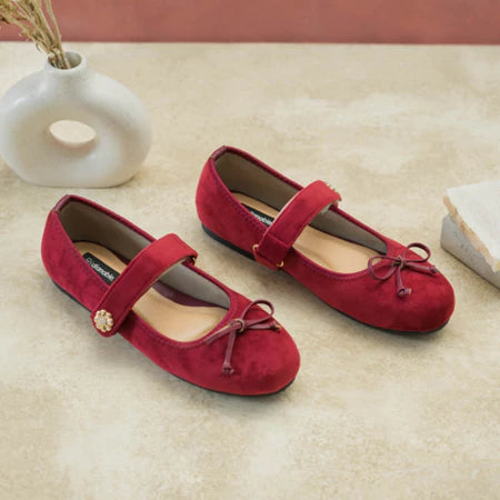Maroon suede flat shoes with a bow by Dianable on a beige surface