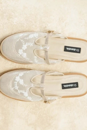 Pair of beige loafers flat shoes with floral patterns on a beige background