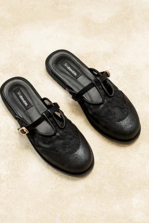 Black loafers flat shoes with decorative straps by Dianable on a beige surface