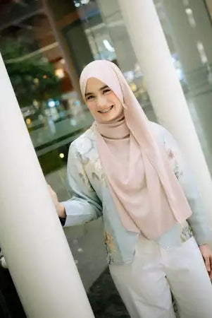Woman wearing a light blue-colored top with floral design by Haidee Orlin in an indoor setting
