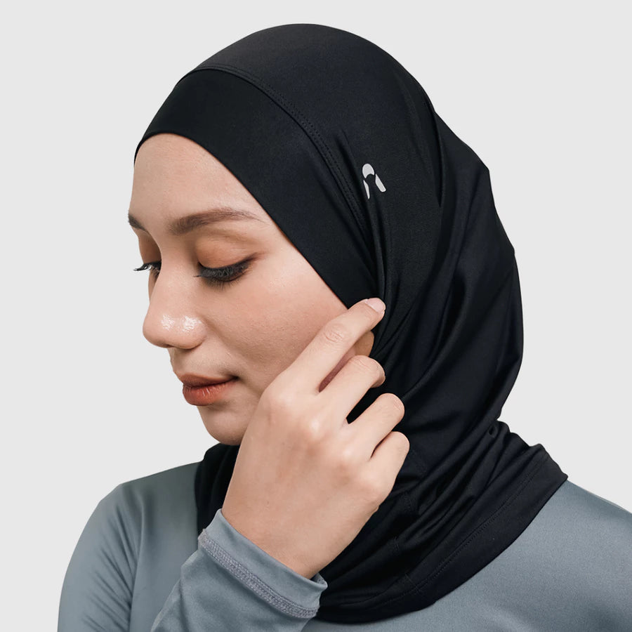 Woman wearing a black sport hijab by HIA on a light gray background