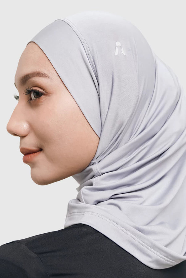 Woman wearing a light gray sport hijab by HIA on a white background
