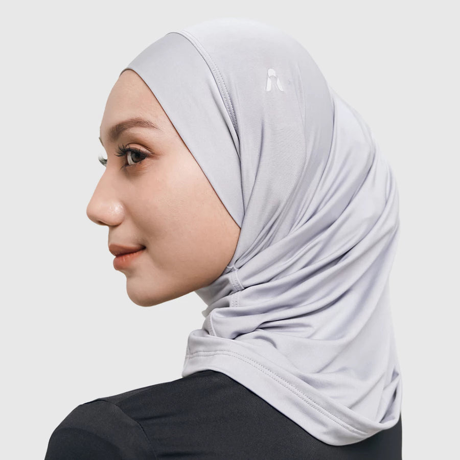 Woman wearing a light gray sport hijab by HIA on a white background