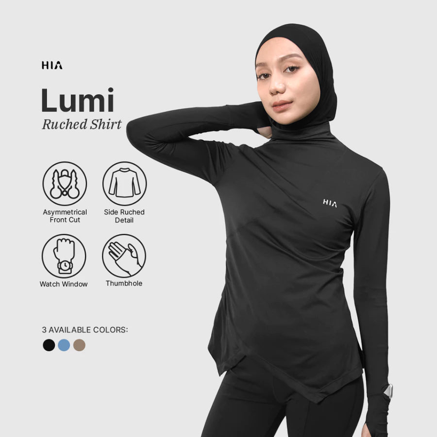 Woman wearing a black HIA Lumi ruched shirt with features highlighted on a light gray background.