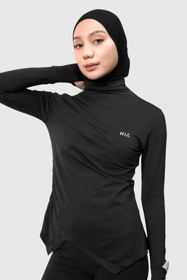 Person wearing a black long-sleeve athletic top by HIA with hijab on a light gray background