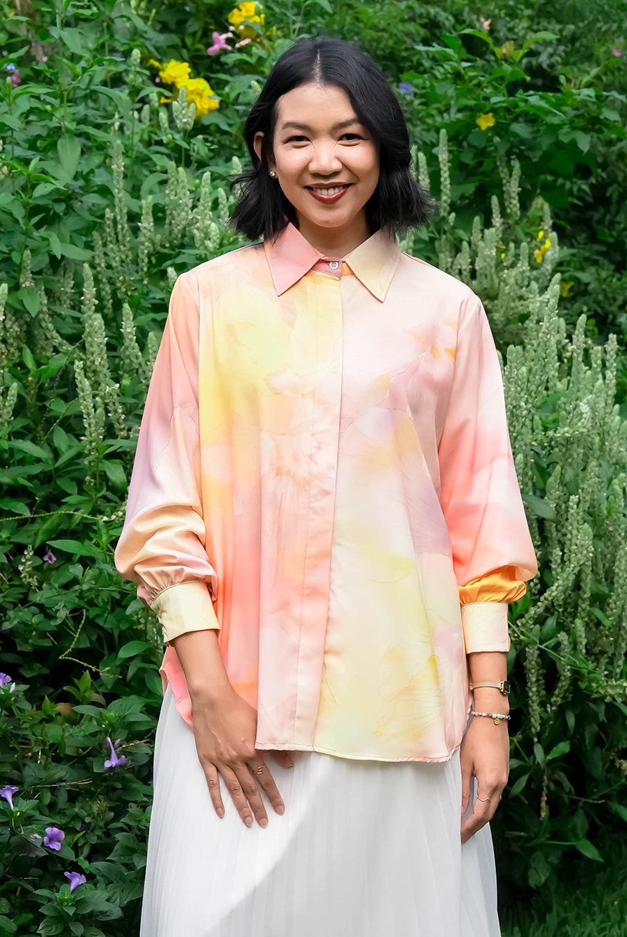 Woman wearing a tie-dye shirt by Puru Kambera standing in a garden