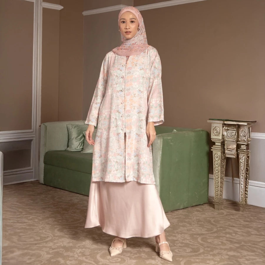 Woman in a light pink tunic by Hijabchic standing in a room with a green sofa and decorative table.
Seorang wanita yang mengenakan tunik berwarna merah muda muda dari Hijabchic sedang berdiri di sebuah ruangan yang dilengkapi dengan sofa hijau dan meja hias.