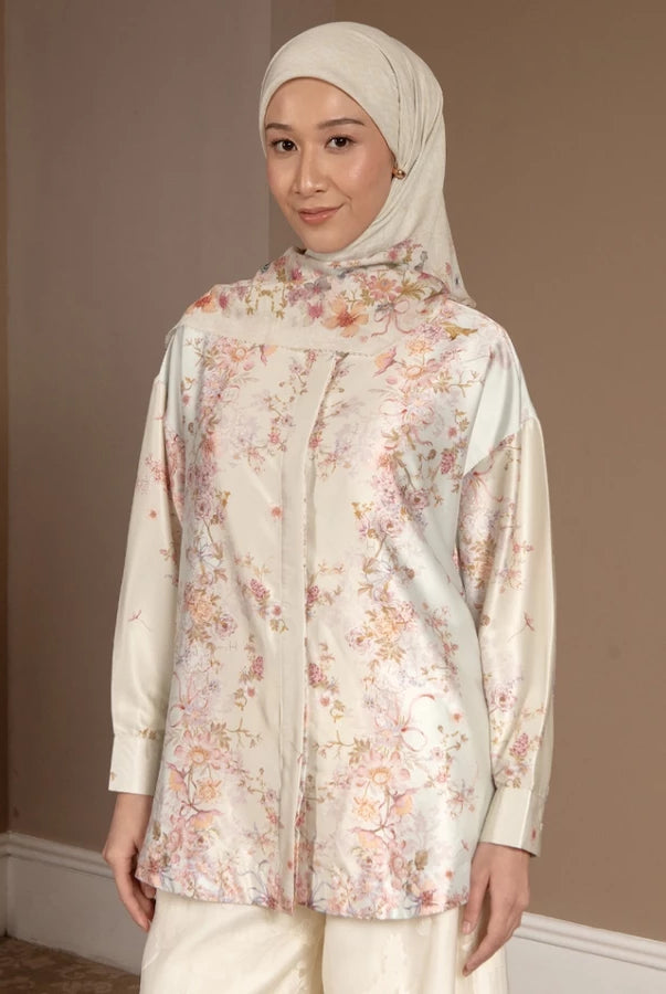 Woman wearing a floral shirt by Hijabchic and hijab against a plain wall