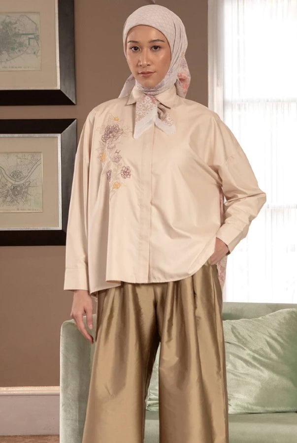 Woman wearing a beige shirt by Hijabchic with a hijab in a living room setting