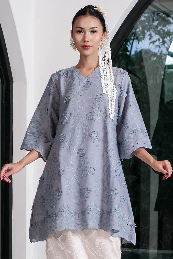 Woman wearing a denim-colored tunic by Holy Peony with floral embroidered.
Seorang wanita mengenakan tunik berwarna denim dari Holy Peony dengan hiasan bordir bunga.