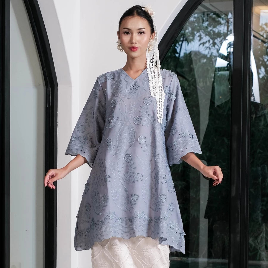 Woman wearing a denim-colored tunic by Holy Peony with floral embroidered.
Seorang wanita mengenakan tunik berwarna denim dari Holy Peony dengan hiasan bordir bunga.