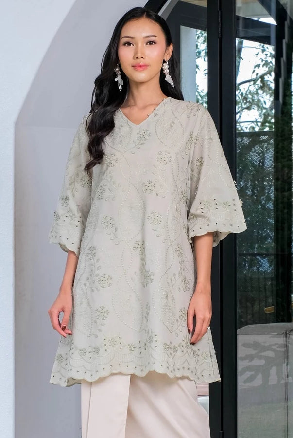 Woman wearing a sage green tunic by Holy Peony with floral embroidered.
Seorang wanita mengenakan tunik berwarna hijau sage dari Holy Peony dengan hiasan bordir bunga.