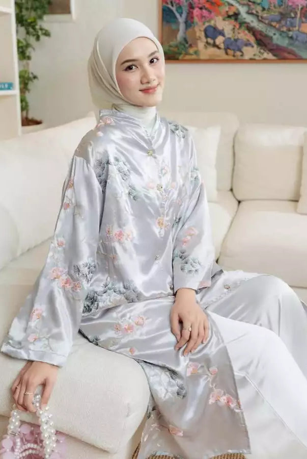 Woman in a blue floral tunic by Haidee Orlin sitting on a couch in a living room.
Seorang wanita mengenakan tunik bermotif bunga berwarna biru karya Haidee Orlin sedang duduk di sofa di ruang tamu.