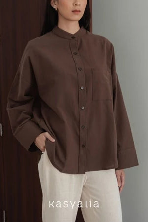 Person wearing a brown shirt with a neutral background, featuring the brand 'kasyalia'.